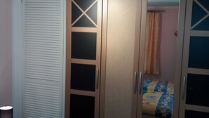 Un dormitorio con cama, armario y cortina.