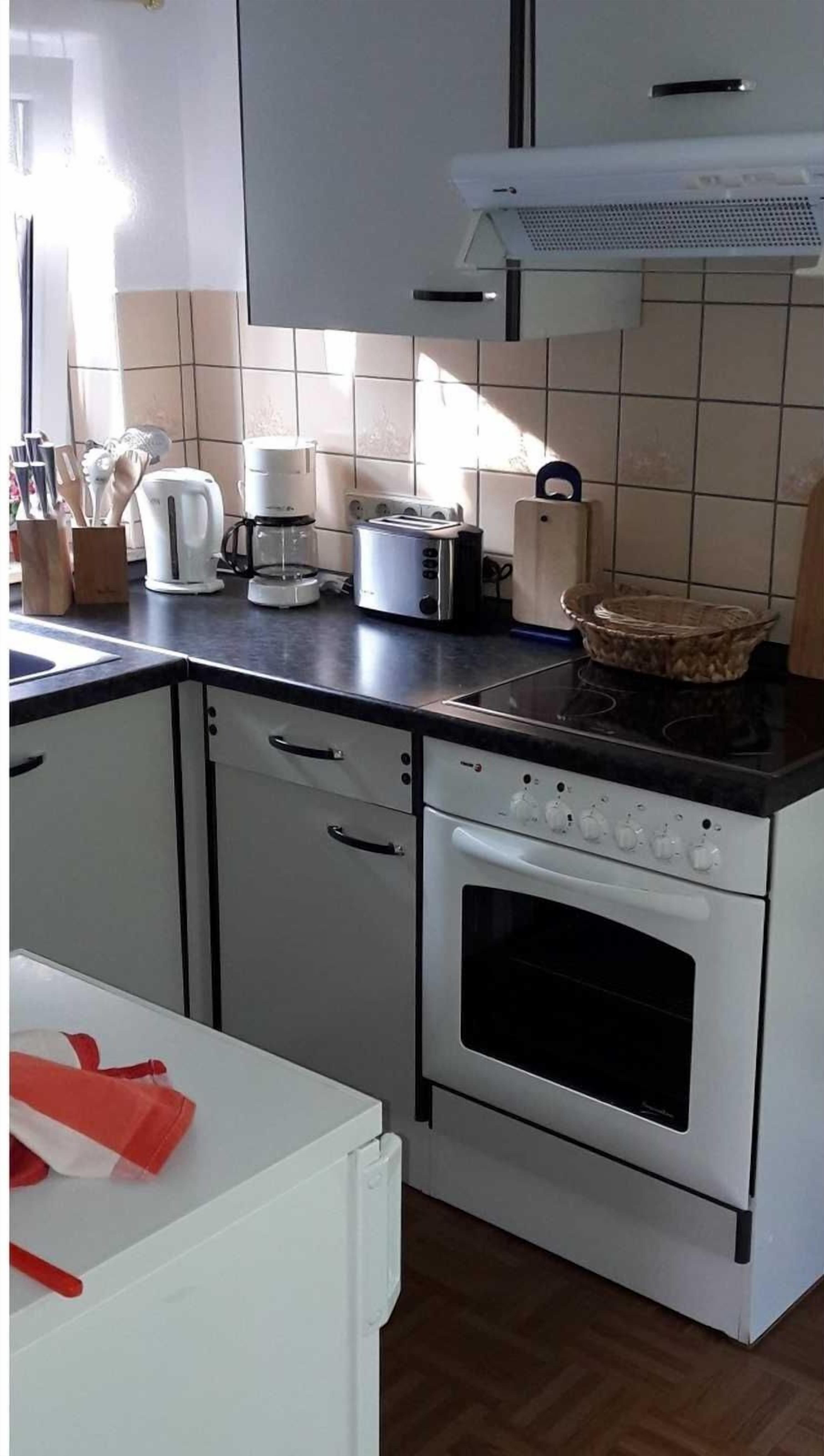 Een keuken met witte kastjes, een fornuis, een broodrooster en een koffiezetapparaat.