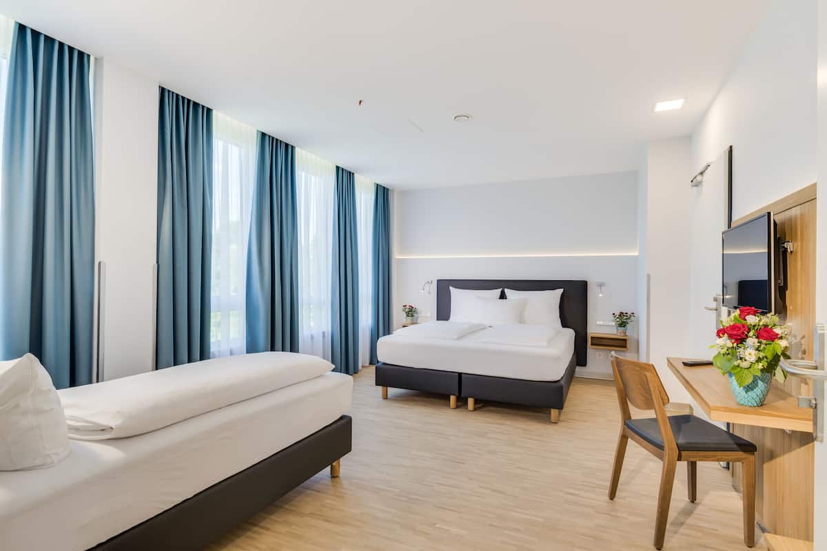 A modern hotel room with a bed, a desk, and a chair.