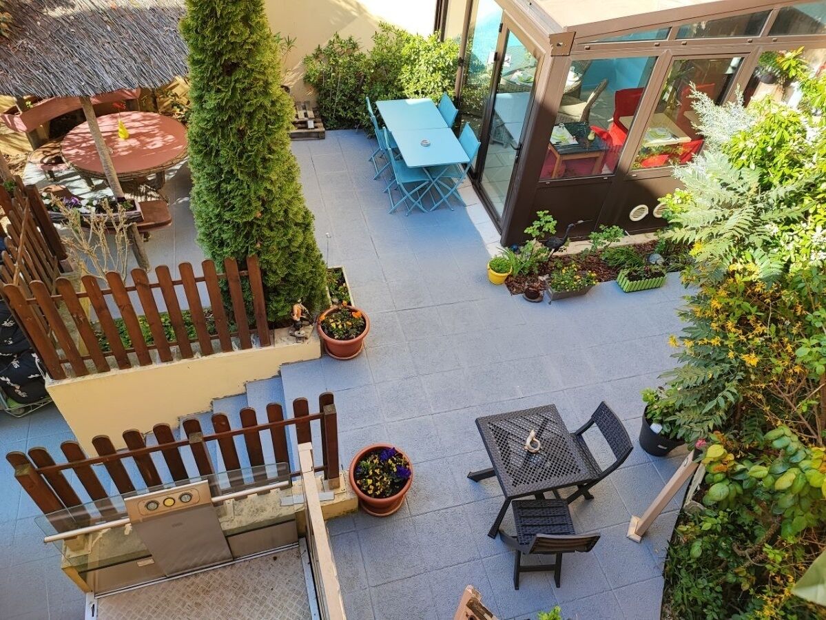 A rooftop patio with outdoor seating, a wooden fence, and potted plants.