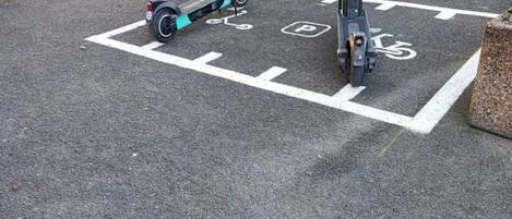 Un espace de stationnement avec deux trottinettes électriques et un vélo.