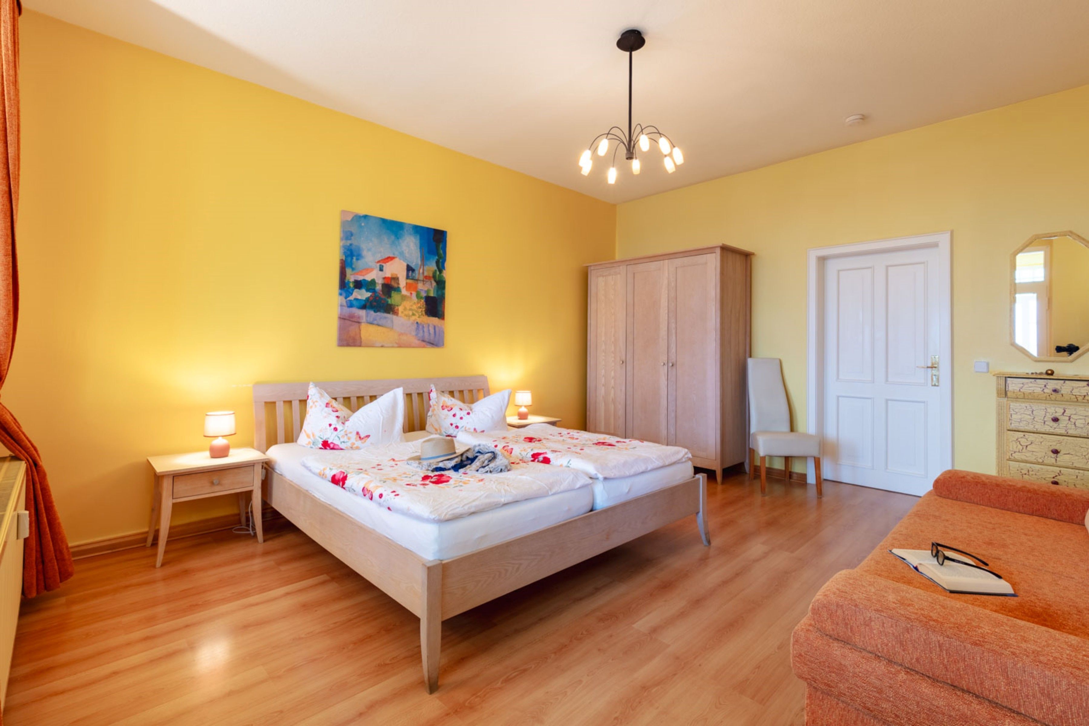 Une chambre à coucher avec un lit, des tables de chevet, une armoire, une porte et un miroir.