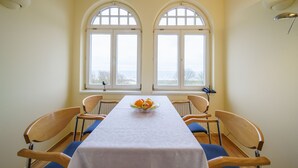 A dining room with a table set for four, two windows with arched tops, and a bowl of fruit on the table. - Vacation apartment 6 - Villa HENRIETTE (Heringsdorf)