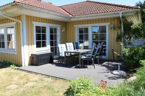 Ein gelbes Haus mit einer Terrasse, einem Tisch und Stühlen sowie einem Fenster.