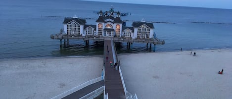 A pier leading to a waterfront building with multiple windows and a dome.