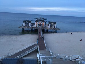 A pier leading to a waterfront building with multiple windows and a dome. - Apartment Bodden - View of the water - Apartments Polchow - directly at the (Glowe)