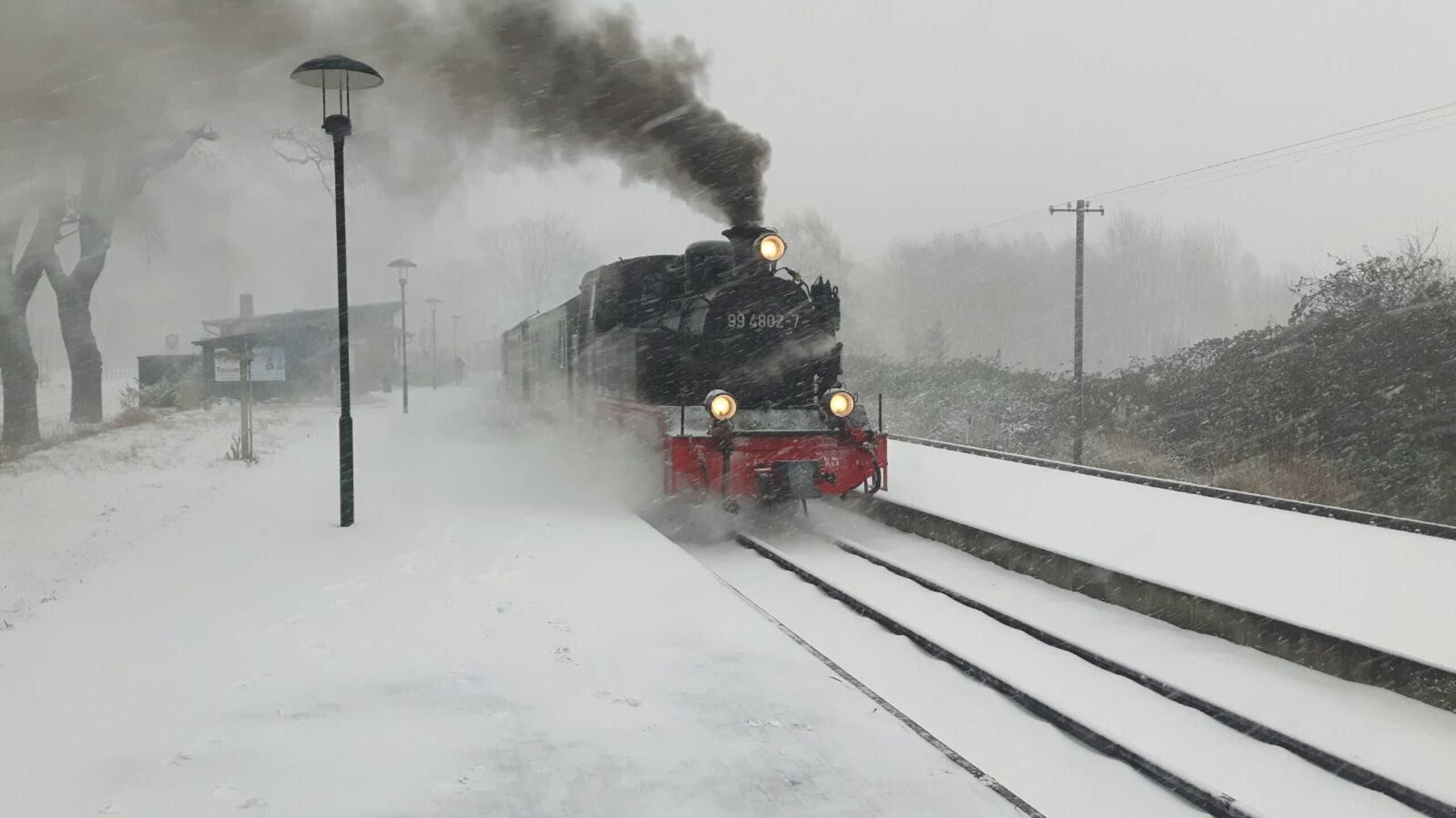 A train with visible numbers on its front, traveling on tracks covered with snow.