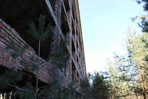 A brick building with a partially open structure, surrounded by pine trees. - Apartment Bodden - View of the water - Apartments Polchow - directly at the (Glowe)
