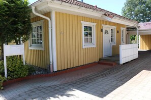 Ein gelbes Gebäude mit weißer Tür, Fenstern und einer kleinen Veranda.