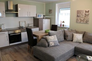 Eine moderne Küche mit Mikrowelle, Backofen und Essbereich. Es gibt ein Sofa mit Zierkissen und ein Fenster mit Schmetterlingsmotiven.