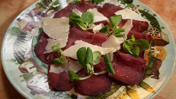 Un plato de embutidos con queso y vegetales verdes.