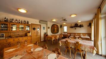 Un restaurant avec des tables et des chaises en bois, un meuble à vin et un ventilateur au plafond.