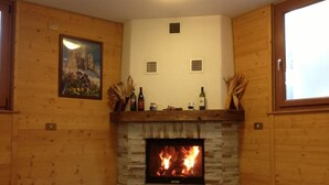Une pièce chaleureuse avec une cheminée en pierre, des murs en bois et un tableau encadré accroché au mur.