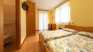 Une chambre avec deux lits, une armoire en bois, un bureau et un téléviseur fixé au mur.
