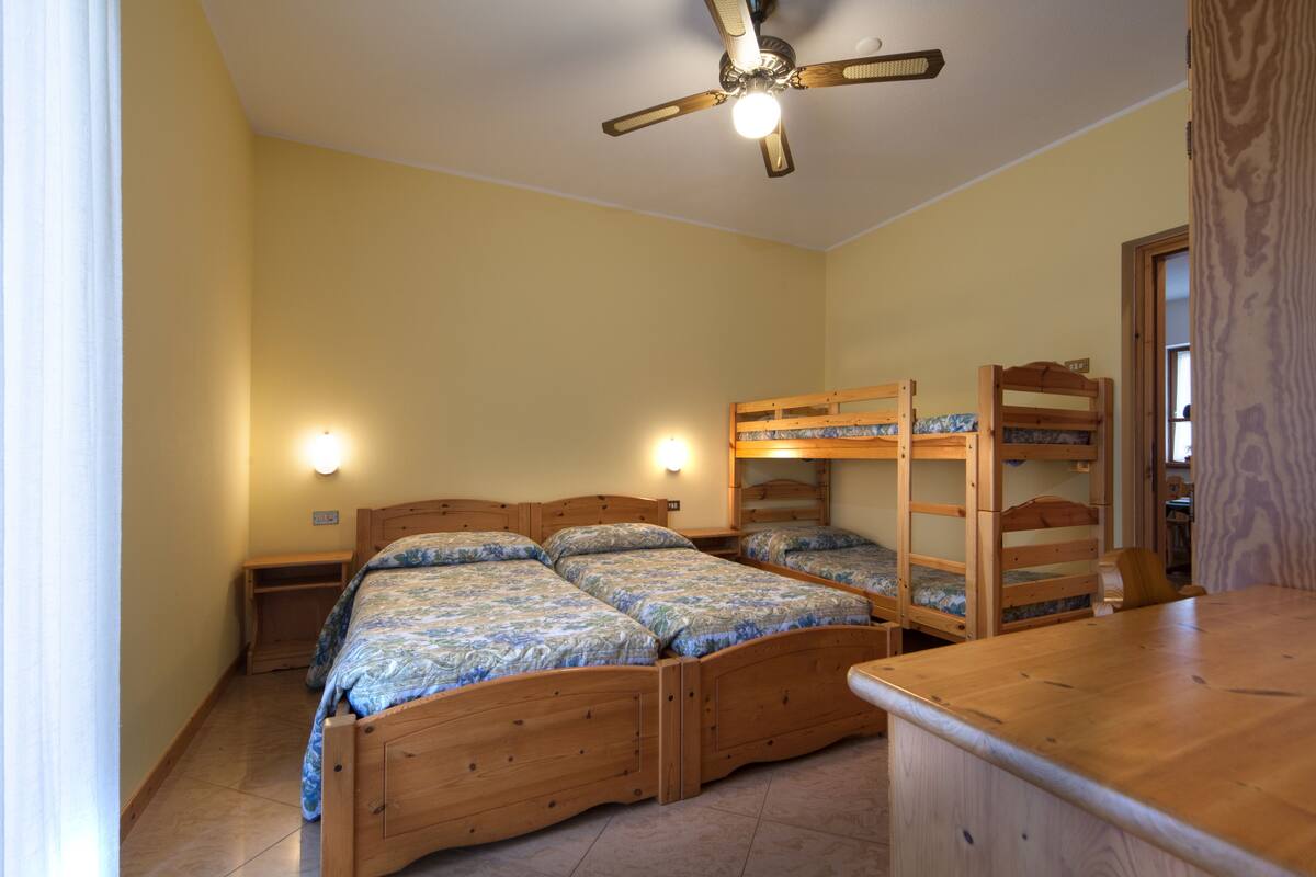 Ein Schlafzimmer mit zwei hölzernen Etagenbetten, einem Deckenventilator und Nachttischlampen.
