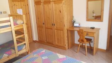 Un dormitorio con literas, un escritorio con silla, armarios de madera y un espejo.