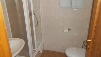 Un baño con cabina de ducha, inodoro y lavamanos.