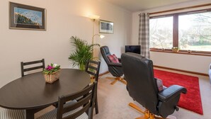 A dining area with a round table, chairs, a plant, and a red carpet. - Springfield View (North Berwick)