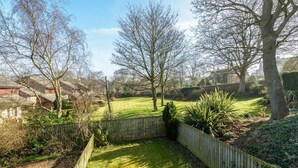A residential garden with a wooden fence, a lawn, and trees. - Springfield View (North Berwick)
