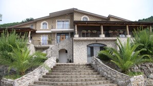 A stone staircase leading to a house with a balcony and potted plants. - Le Rocce (Sant'Agata de'Goti)