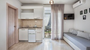 Une cuisine moderne avec des meubles blancs, un lave-vaisselle intégré et un coin repas comprenant une table et des chaises.