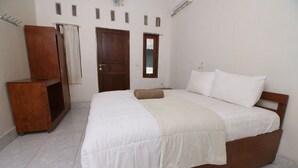 A bedroom with a wooden bed, a wooden wardrobe, a small window, and a door. - Sari Laut (Gili Meno)