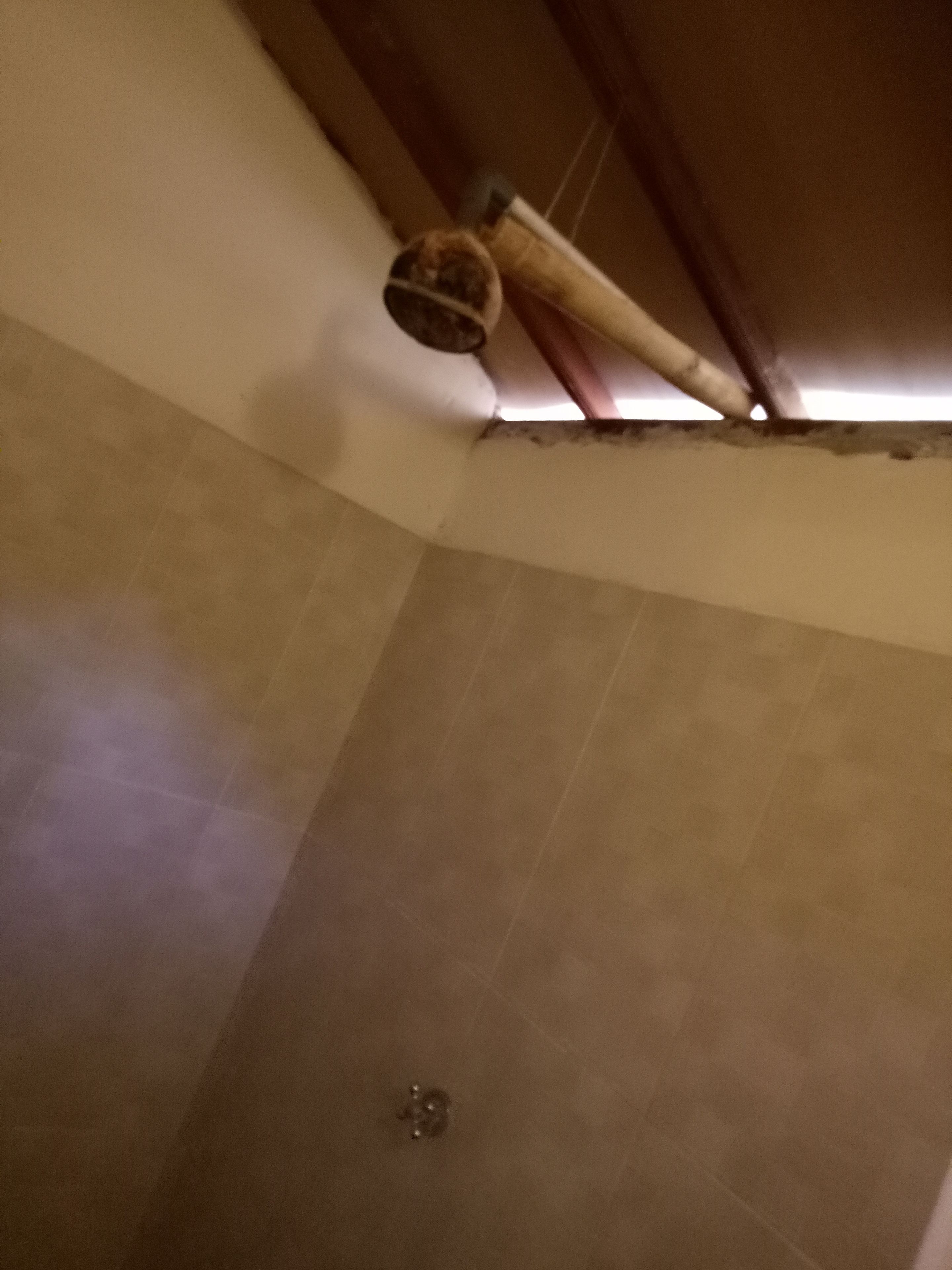 Una esquina de una habitación con suelo de baldosas, una puerta de madera y un accesorio de fontanería a la vista.