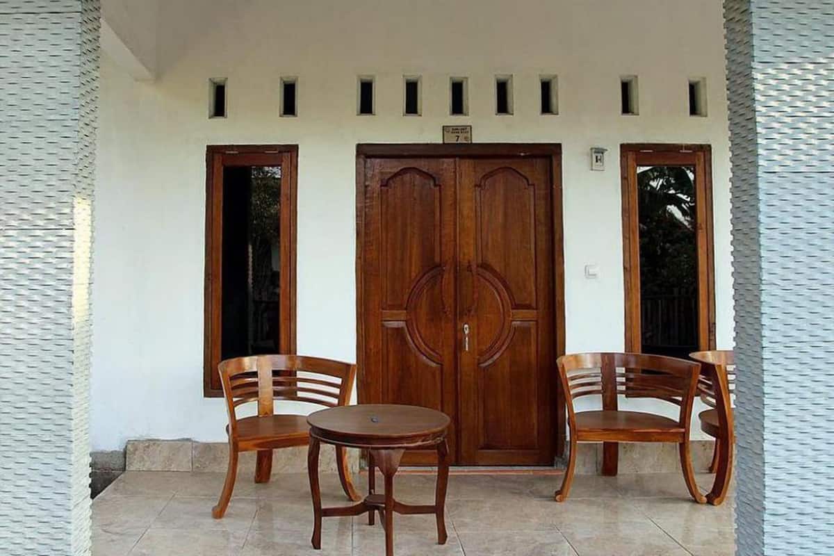A building entrance with a double wooden door, two wooden chairs, and a small round table.