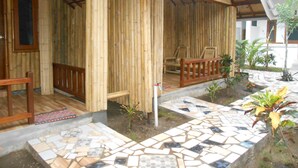 A wooden building with a tiled patio and a covered seating area. - Sari Laut (Gili Meno)