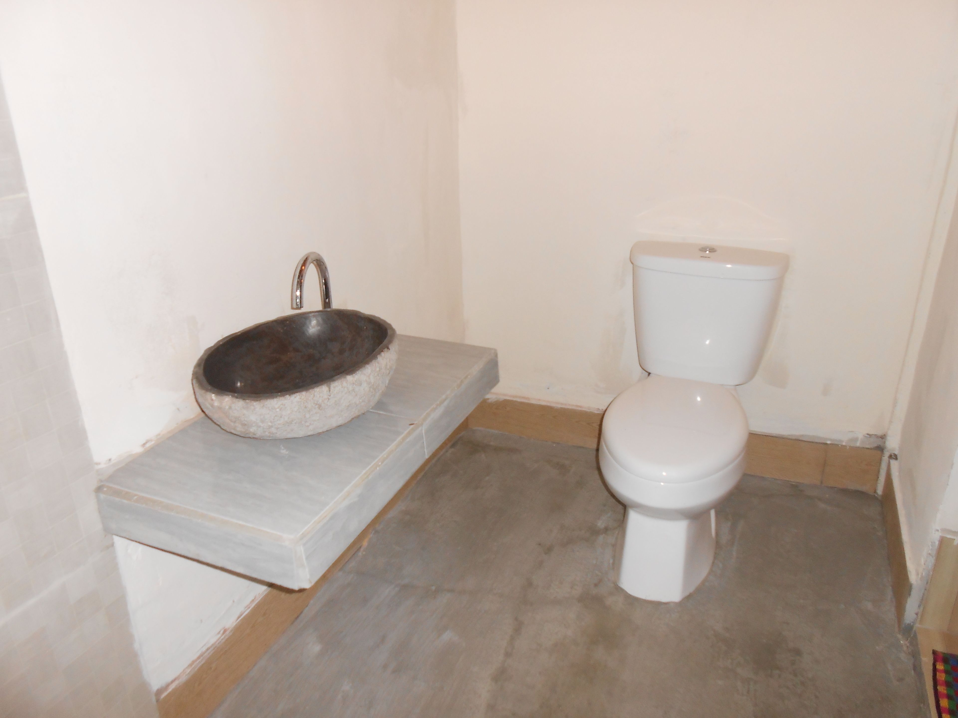 Uma casa de banho com lavatório de pedra e sanita branca.