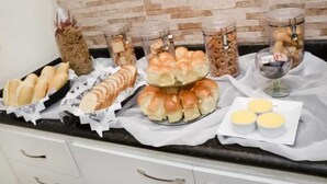 A kitchen counter with various food items including bread, rolls, and jars of snacks. - Pousada Âncora de Ouro (Cabo Frio)