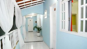 A hallway with light blue walls, white doors, and a potted plant. - Pousada Âncora de Ouro (Cabo Frio)