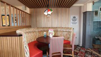Een gezellige zithoek met houten plafond, een ronde tafel en een bord dat aangeeft dat er gebraden rundvlees en Yorkshire pudding te verkrijgen is.