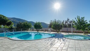 A swimming pool with a tiled deck, surrounded by trees and a mountain in the background. - Nonno Luigino (Vico Equense)