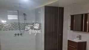 A modern bathroom with a glass-enclosed shower, a vanity with a mirror, and a tiled floor.