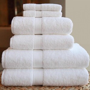 A stack of white towels arranged in a pyramid shape on a woven surface. - B&B Kèbele (Roana)