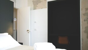 A hotel room with a bed, a chair, and a door leading to another room. - The Station Napoli (Naples)