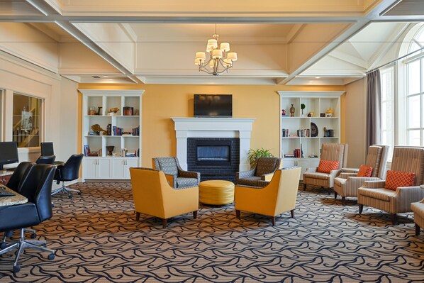 A spacious lobby with a fireplace, seating area, and bookcases.