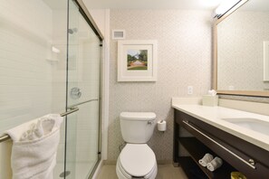 A bathroom with a glass shower enclosure, a toilet, a sink, and a towel rack.