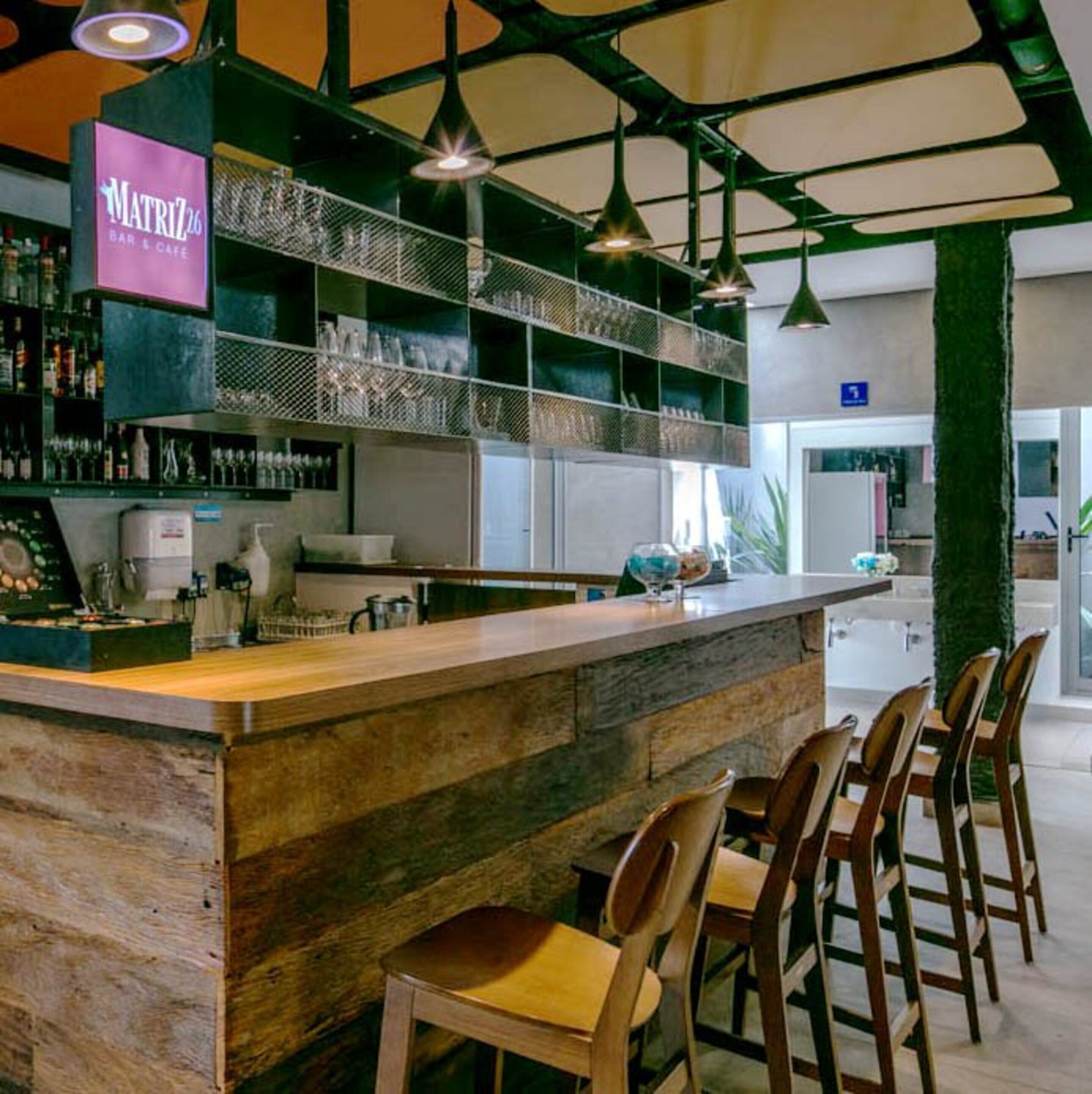 Un espace bar avec un comptoir en bois, des luminaires suspendus et des tabourets de bar.