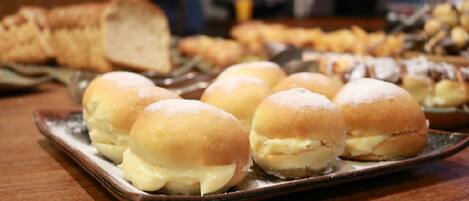 A tray of cream-filled buns on a wooden table.