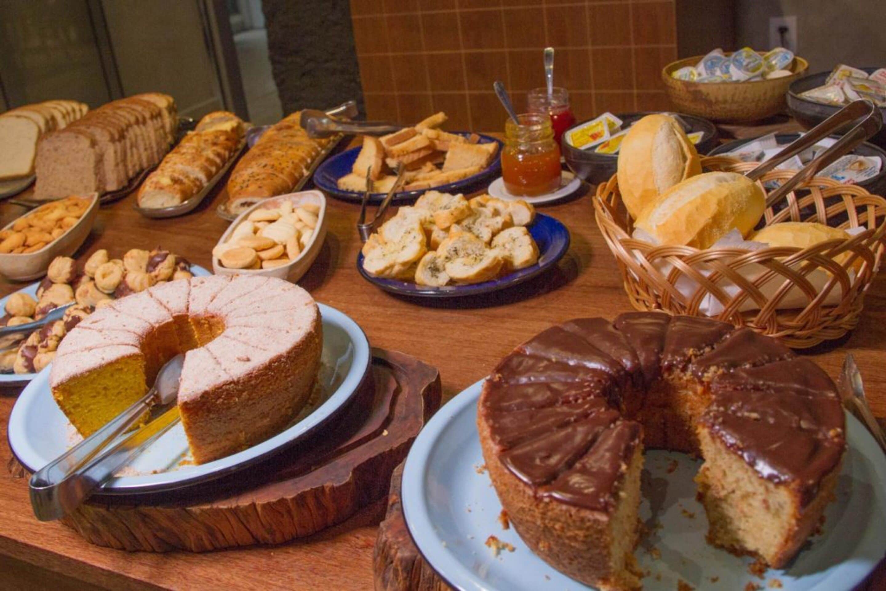 A buffet table with various food items including cakes, bread, and pastries.