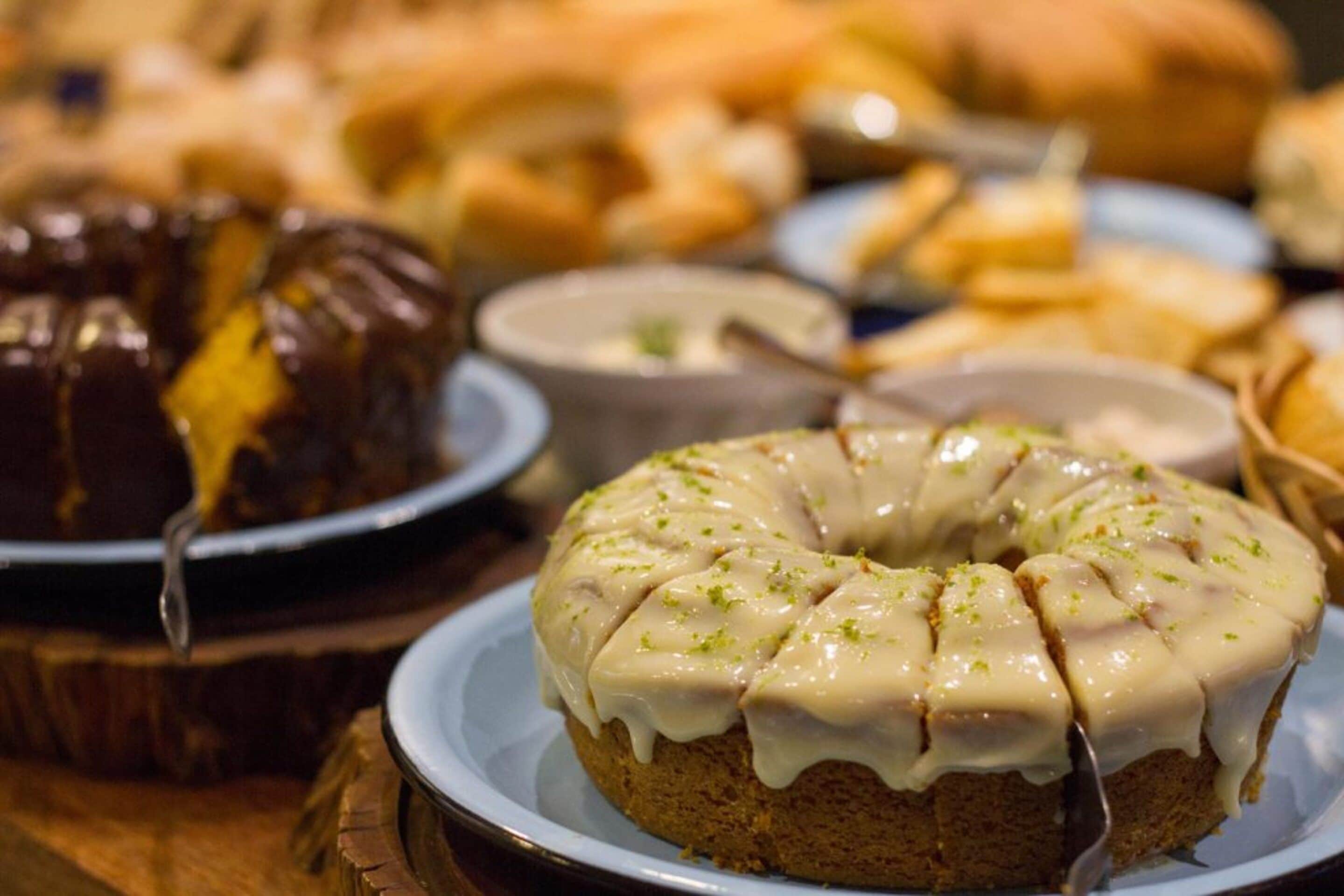 Un assortiment de desserts, notamment un gâteau en forme de couronne recouvert d’un glaçage blanc et un gâteau au chocolat à la finition brillante.