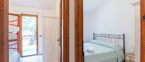 Une chambre à coucher avec un lit, un cadre de porte en bois, une petite table de chevet et une vue sur l’extérieur.