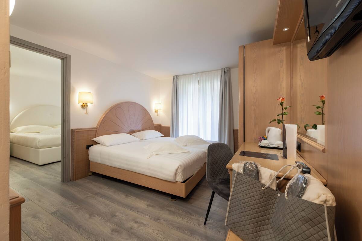 A hotel room with a bed, bedside table, chair, and a TV mounted on the wall.