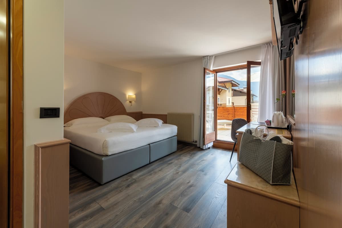 A modern hotel room with a bed, a desk, and a view of a mountain.