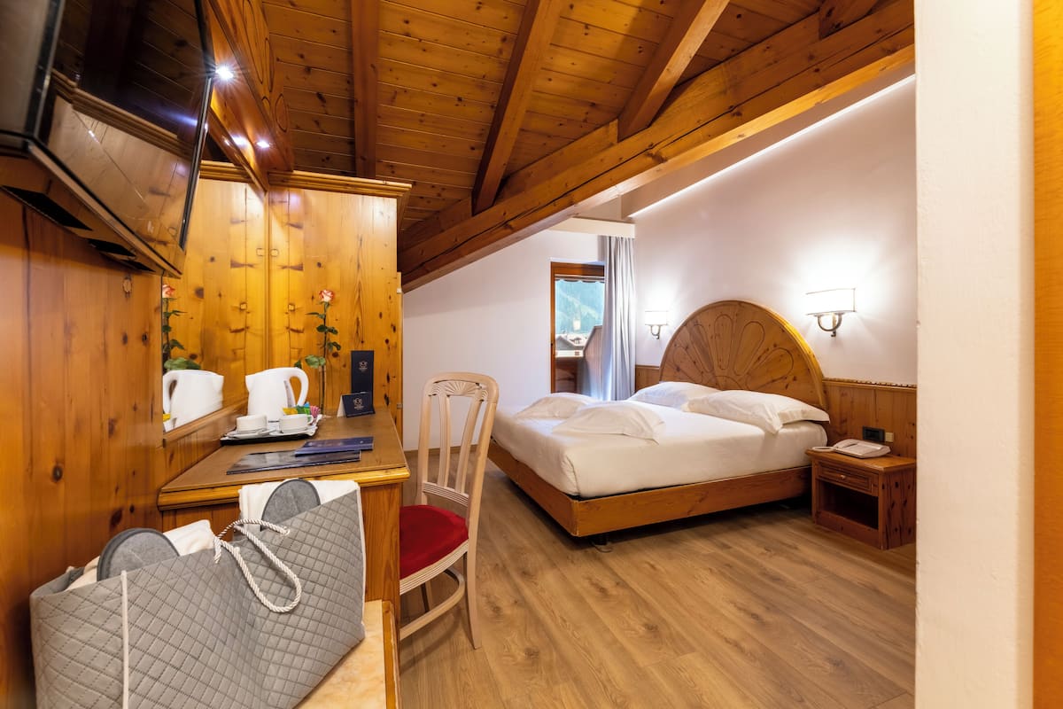 A wooden-paneled room with a bed, a desk, and a chair.