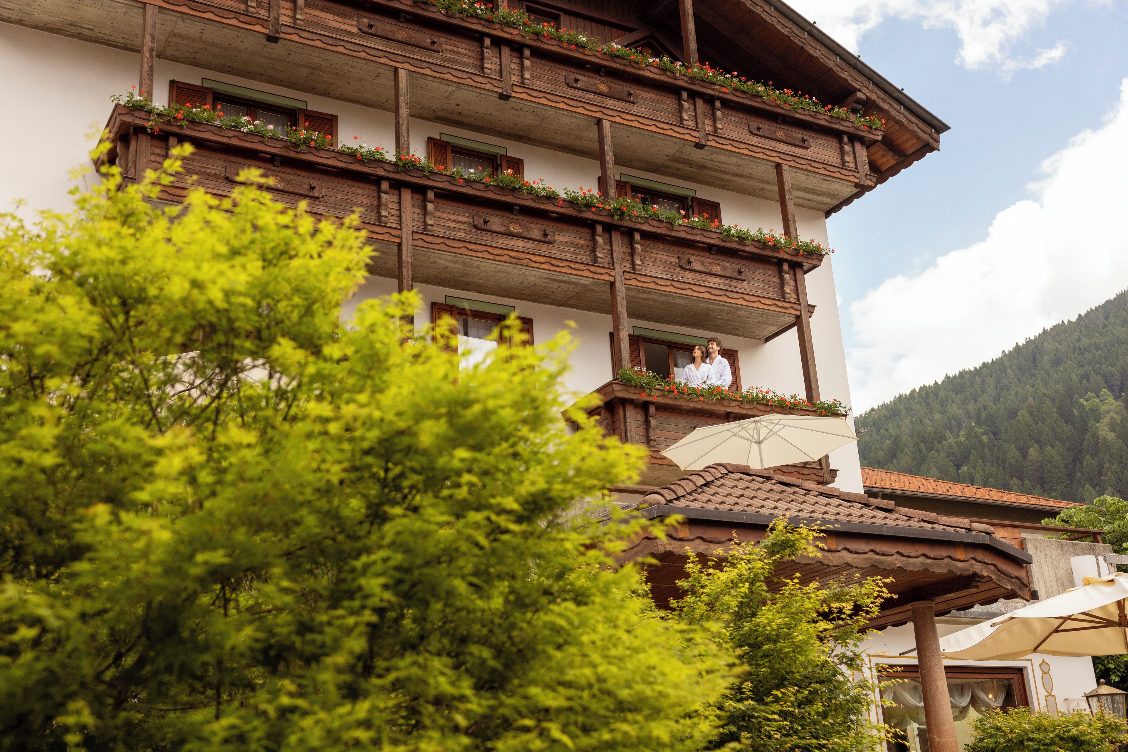 Un edificio a più piani con balconi decorati da fiori, immerso nel verde.
