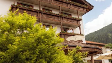 Un edificio a più piani con balconi decorati da fiori, immerso nel verde.