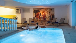 Une piscine intérieure dotée d’un plafond étoilé et d’une fresque représentant un lion et une femme.
